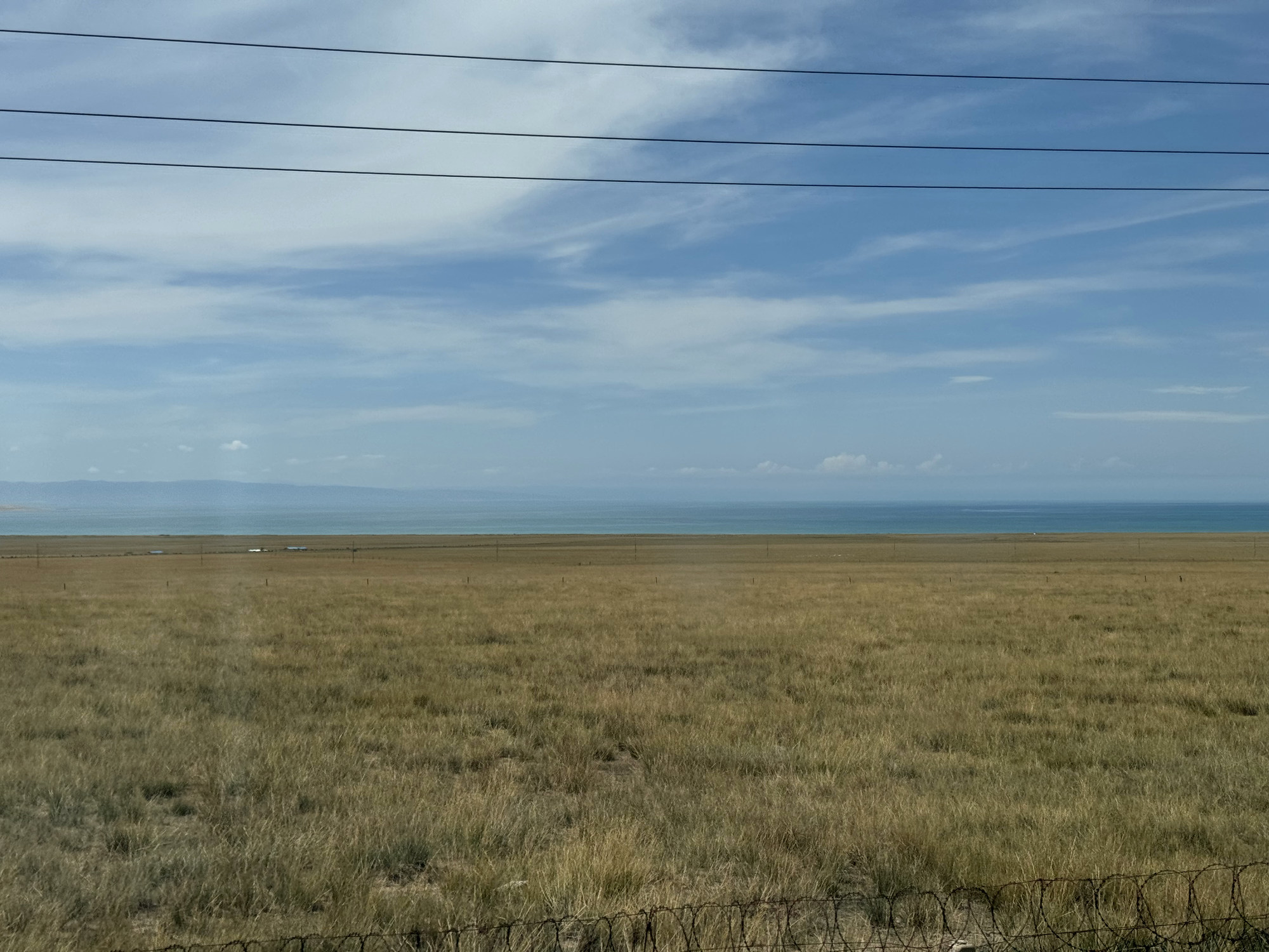 Qinghai Lake, grassland, and layered clouds seen from the train