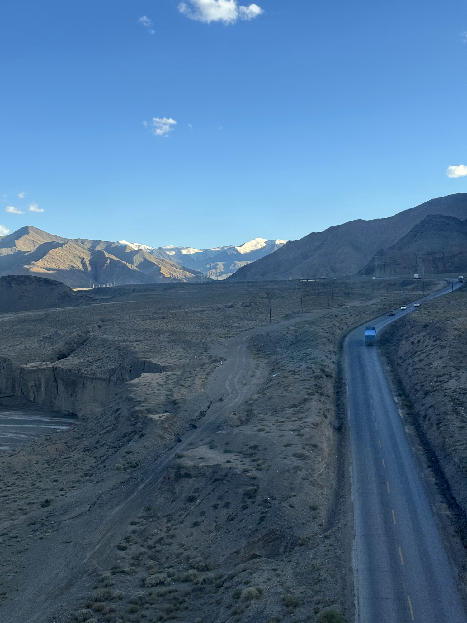 A road beside the Qinghai–Xizang Railway leading toward distant snow mountains