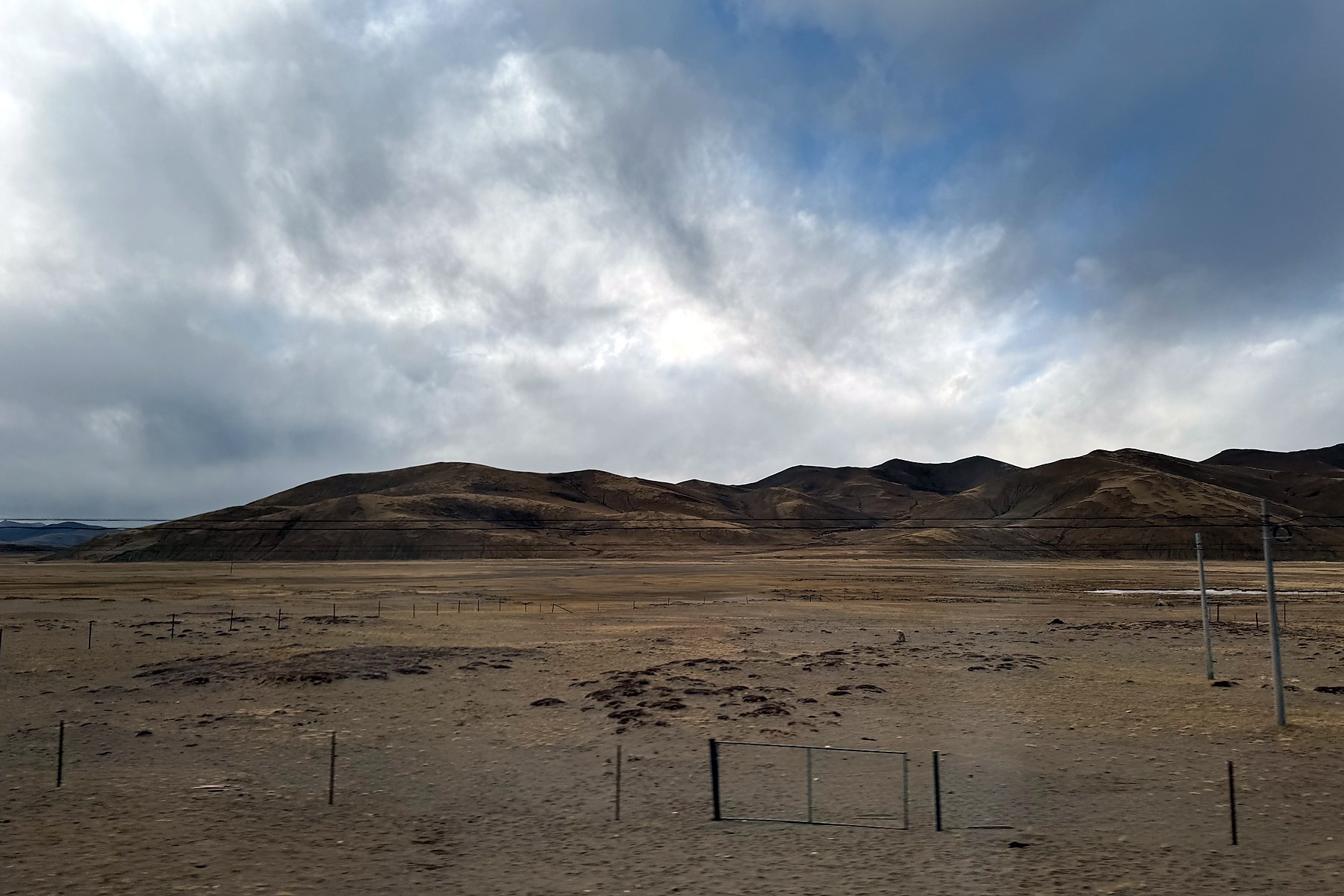 Low cloud over an open winter plateau and rounded mountains