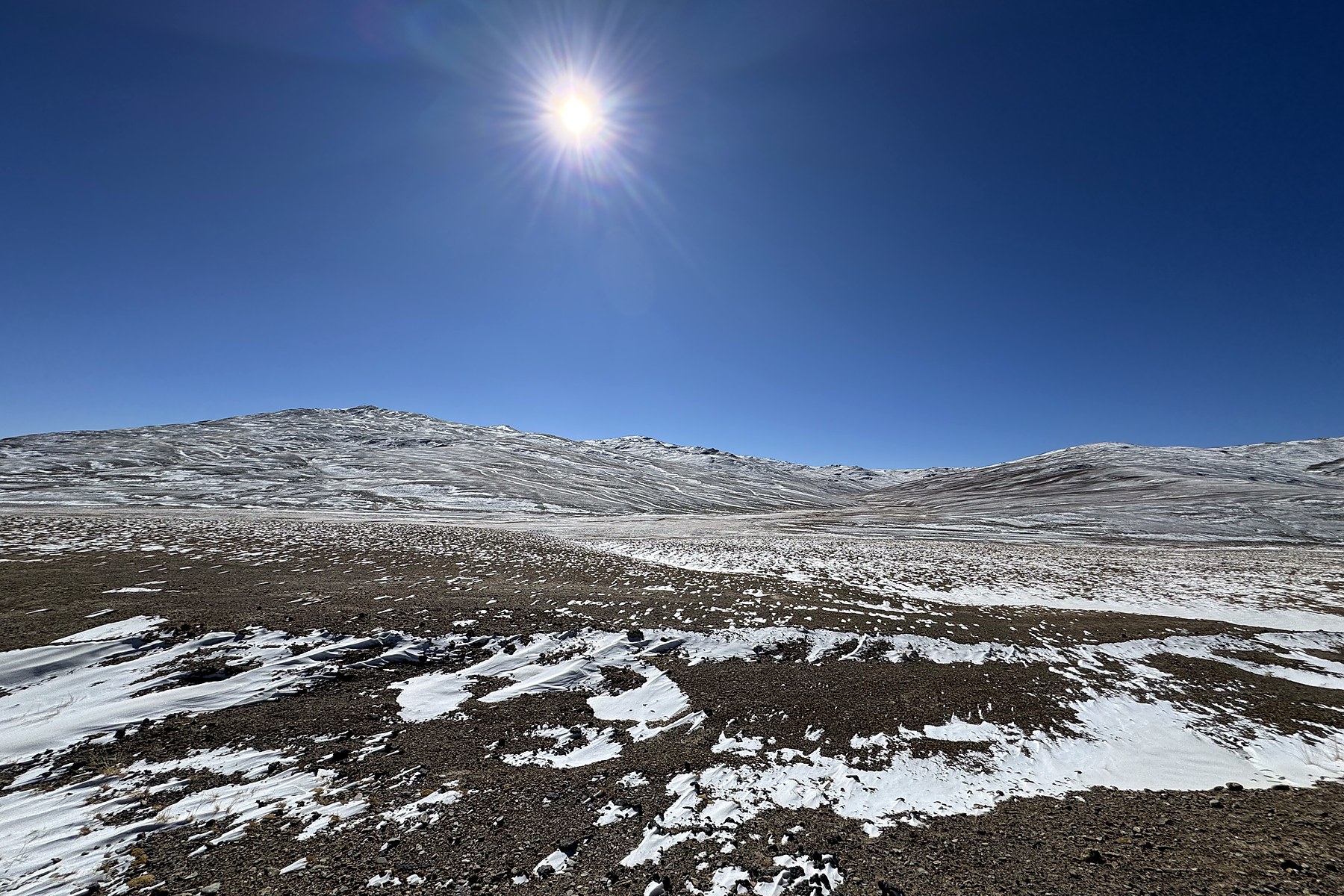 A high plateau slope with broken snow under intense sunlight