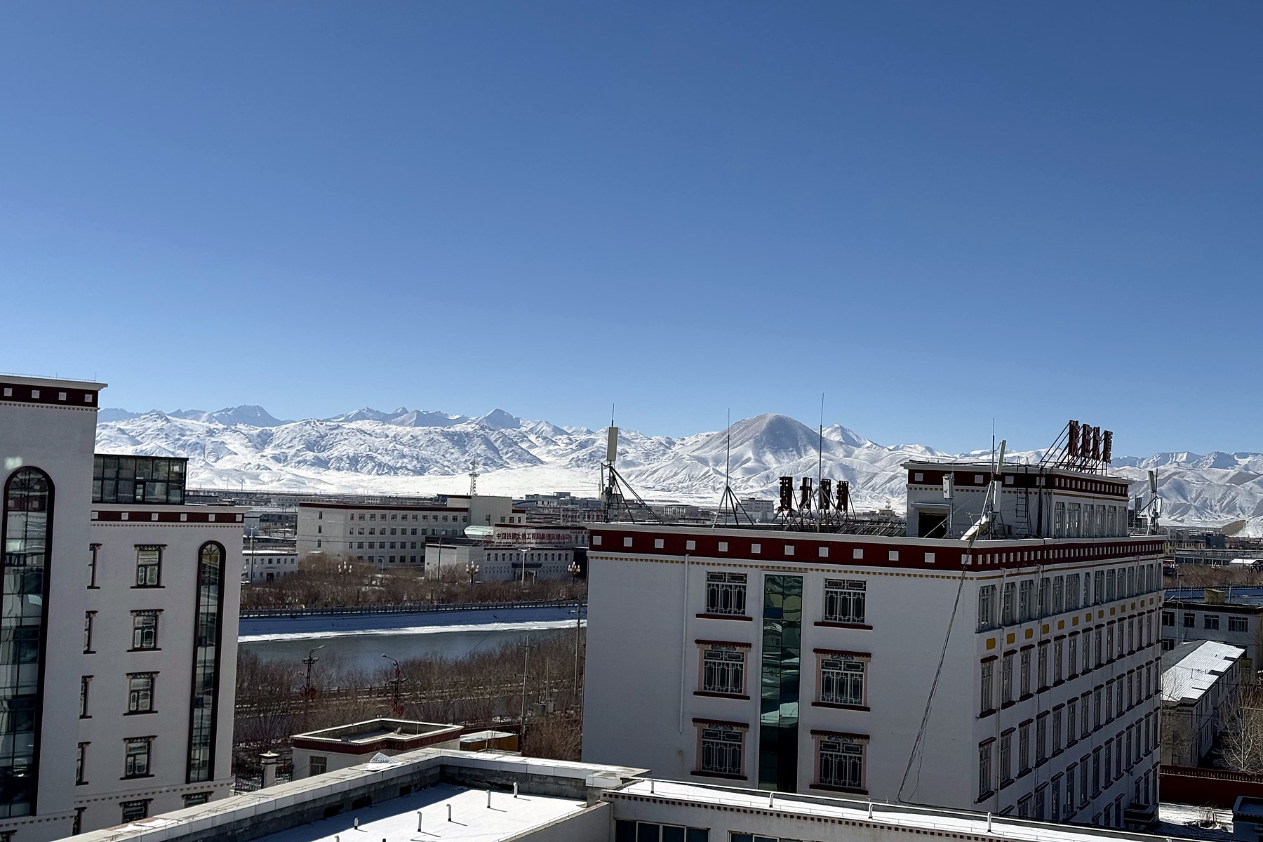Shiquanhe under a clear sky with a long snow-covered range beyond the town