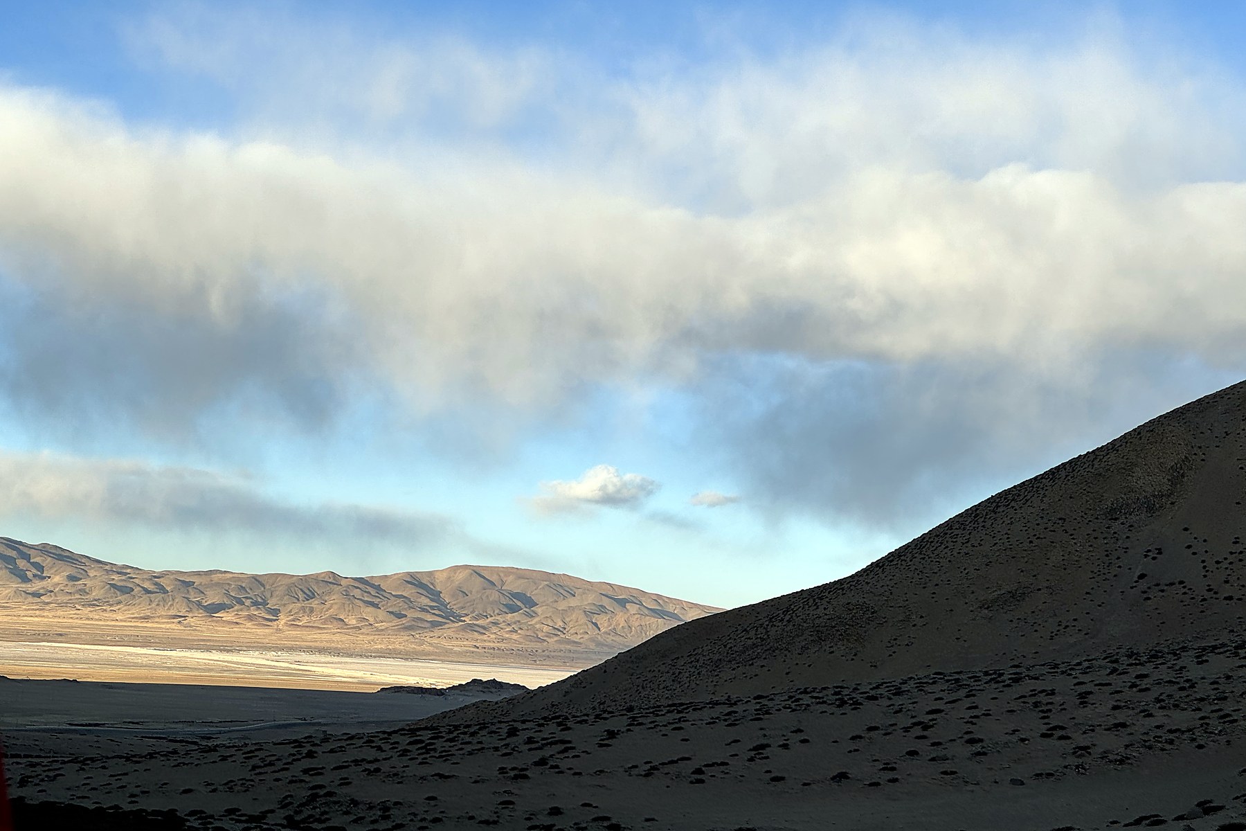 An evening plateau valley under cloud with a faint rainbow