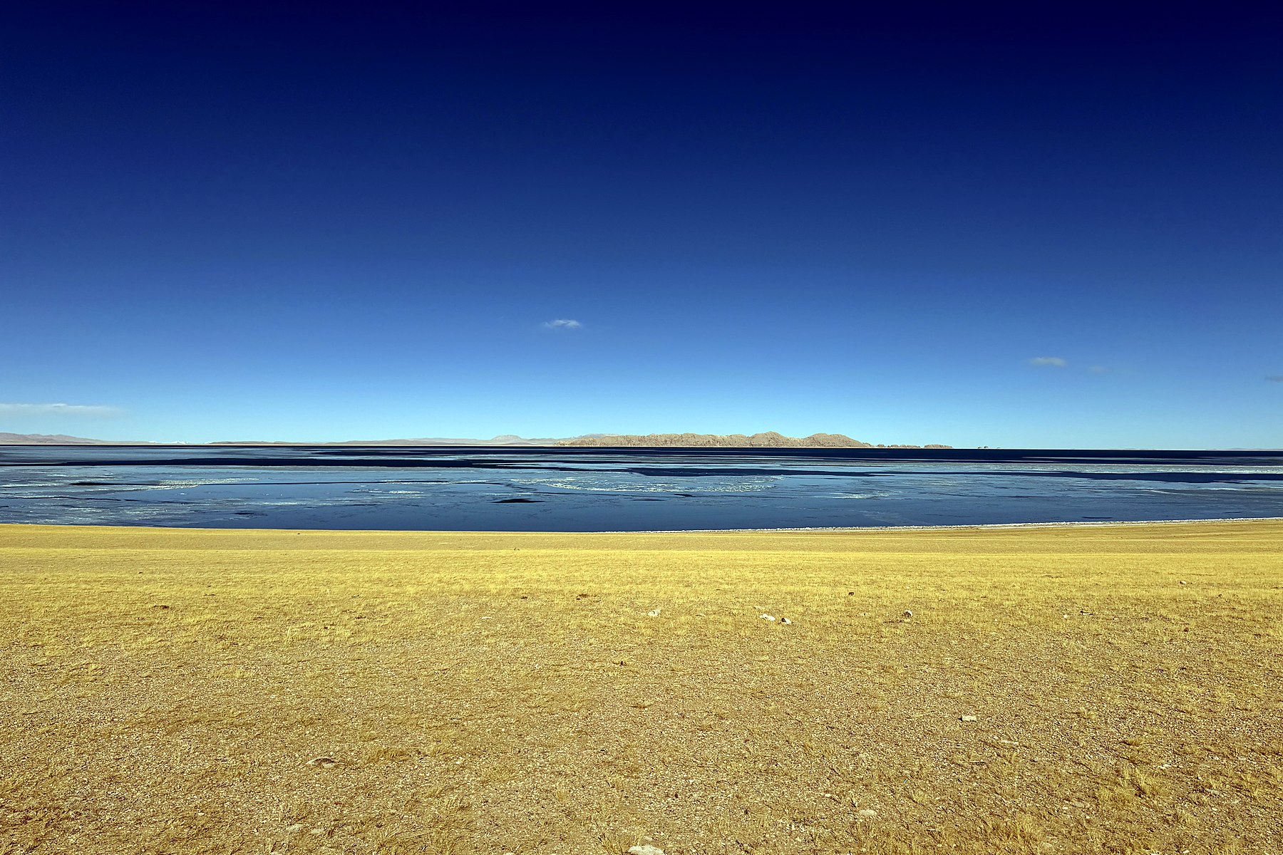 Deep blue water, a pale winter shore, and low mountains at western Siling Co