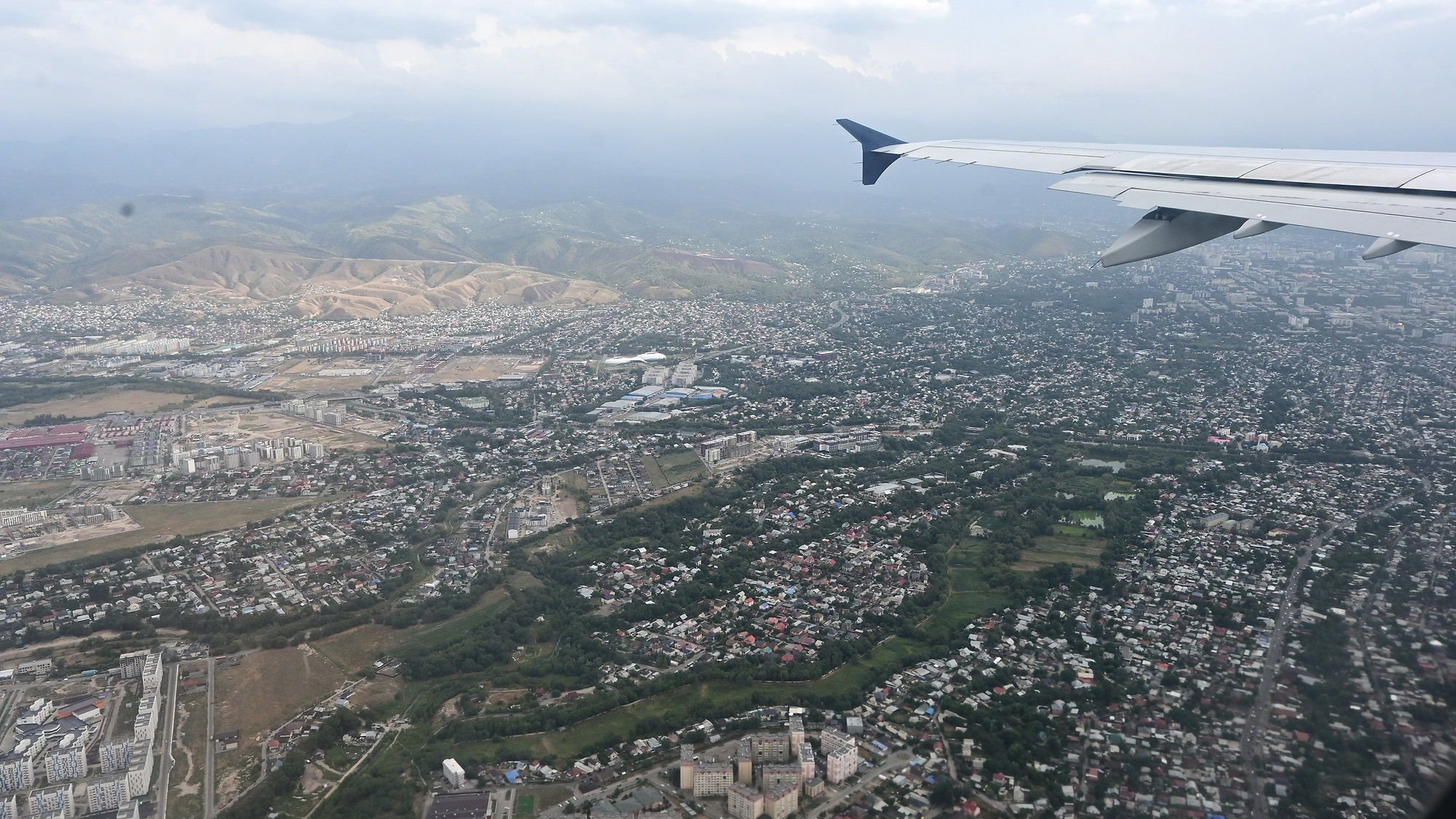 An aerial view of Almaty, with the city extending toward distant mountains
