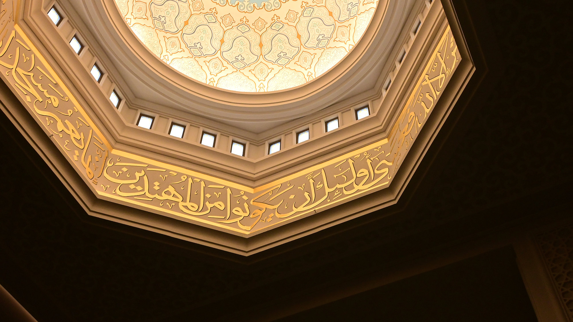 Calligraphy and warm light inside the dome of the Astana Grand Mosque