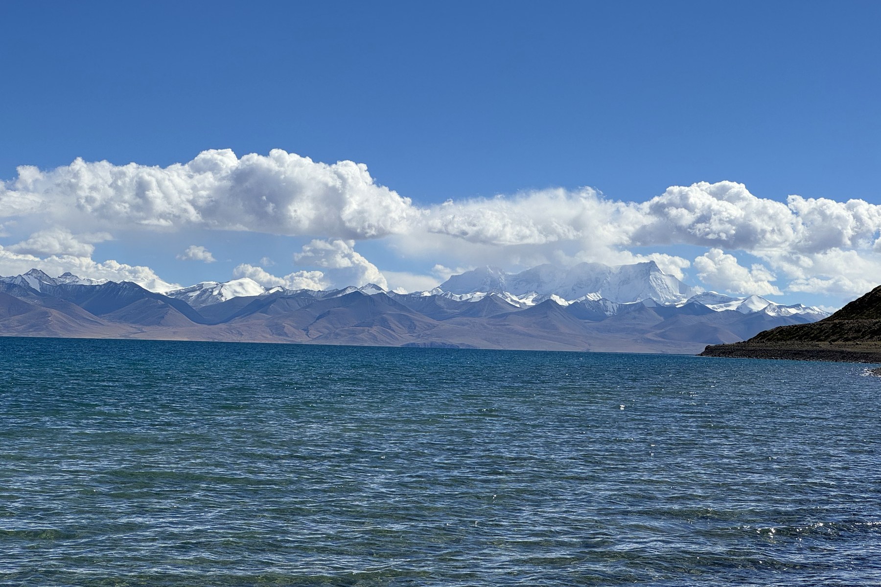 Namtso, distant snow-covered mountains, and a low headland at the right edge