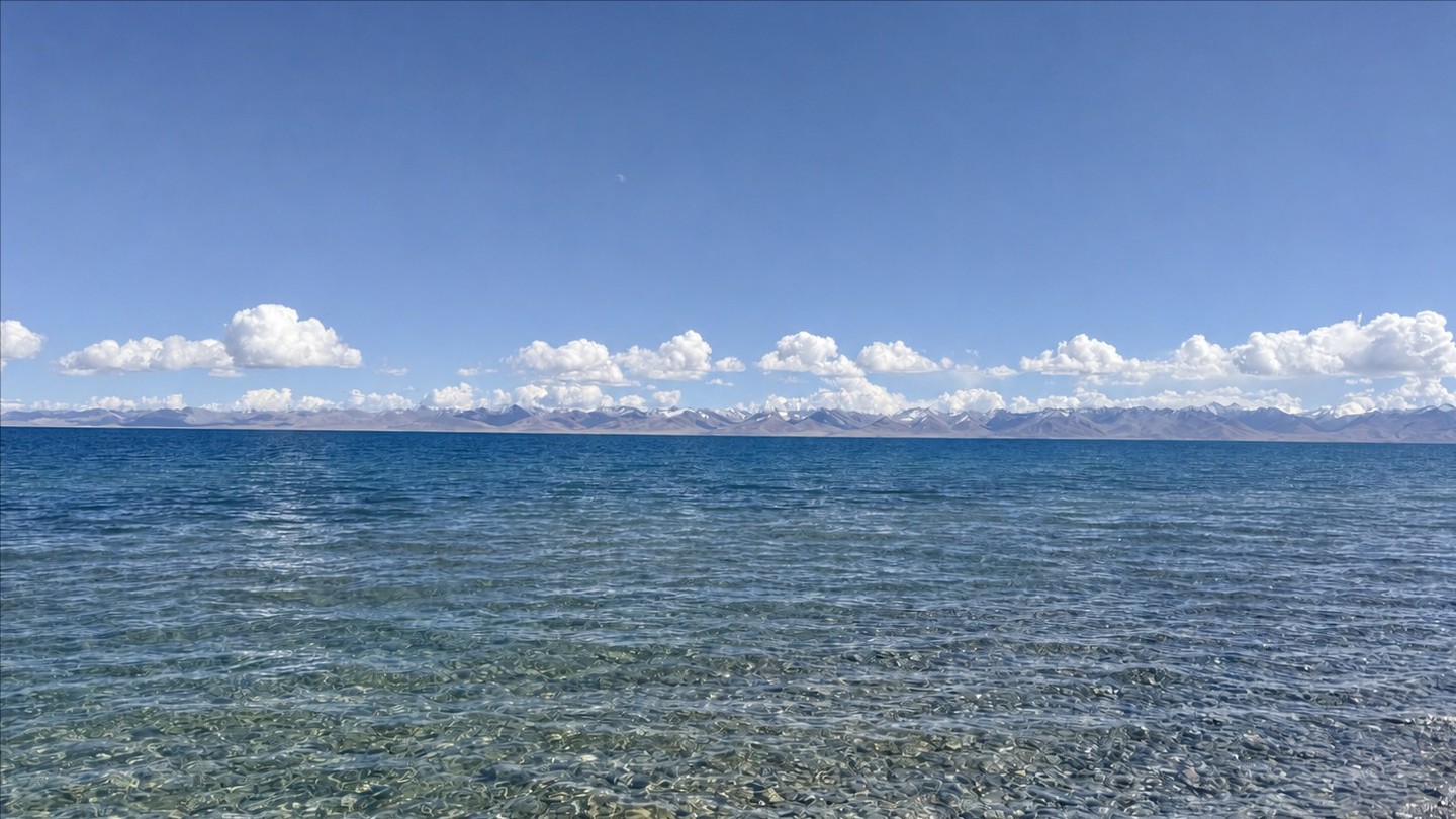 Clear water, clouds, and distant snow-covered mountains on Namtso’s northern shore