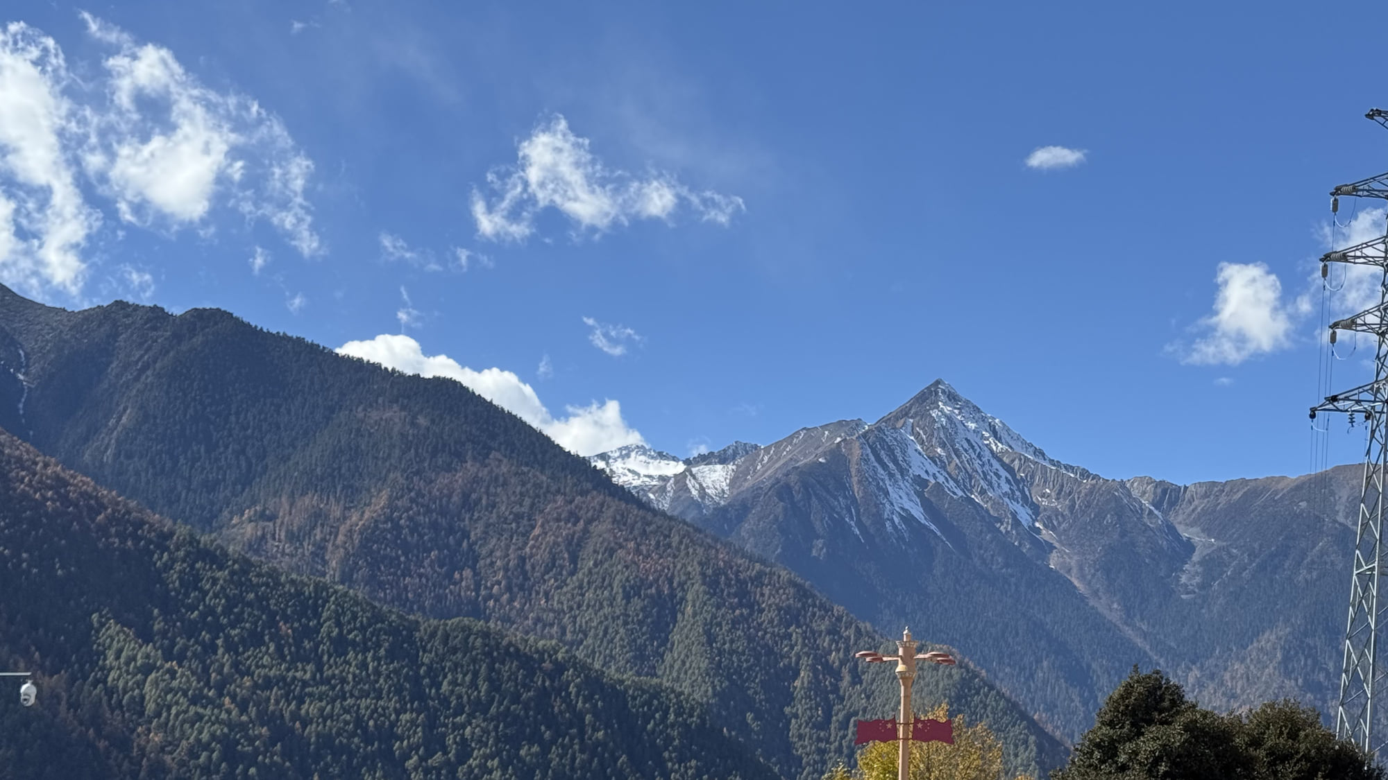 Snow-covered mountains and power-transmission infrastructure in a valley en route to Ranwu Lake