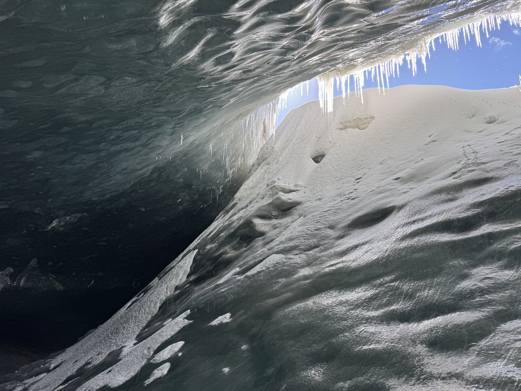 A translucent opening and slender icicles seen from inside the ice