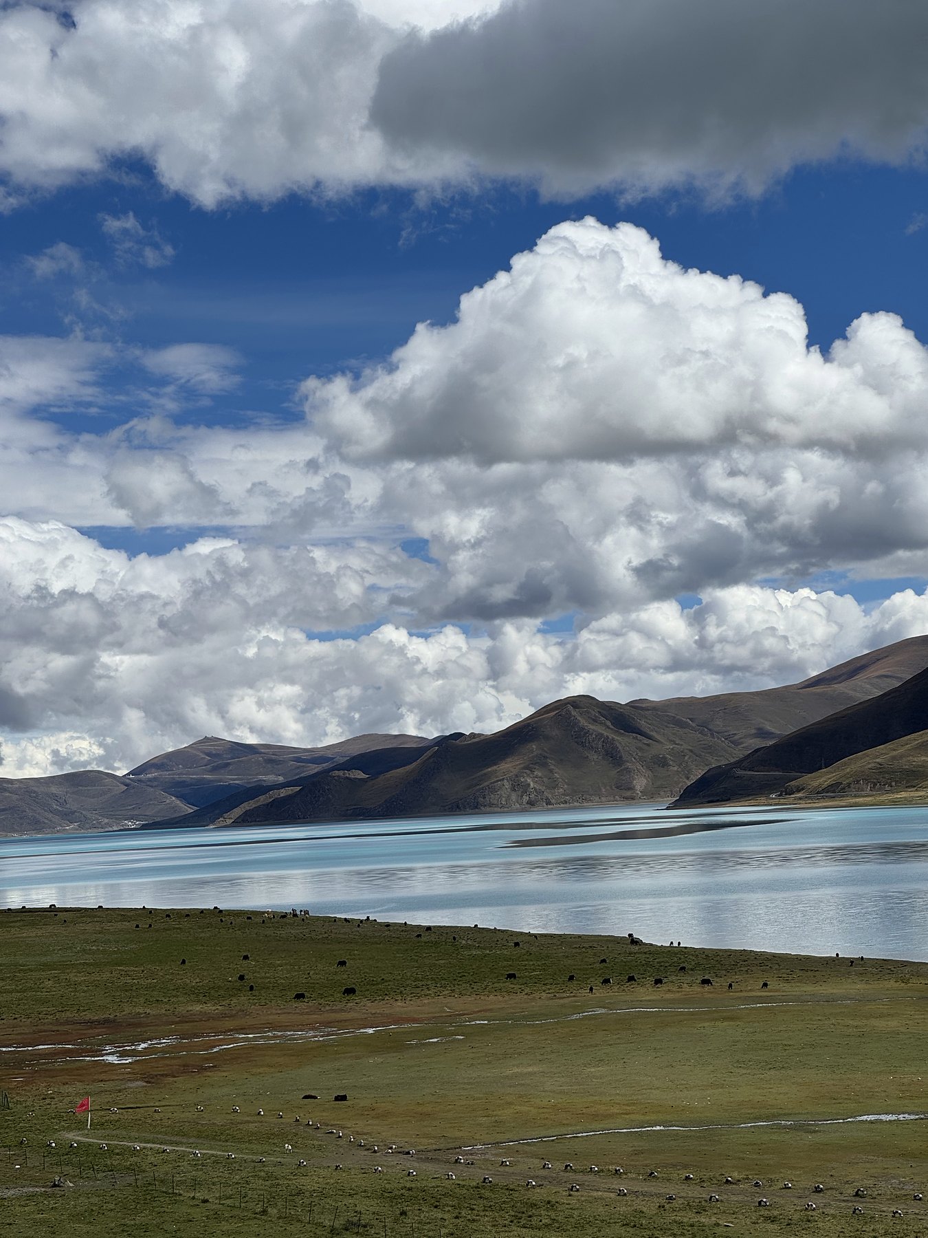 A lower view across deep blue Yamdrok with layered mountains beyond