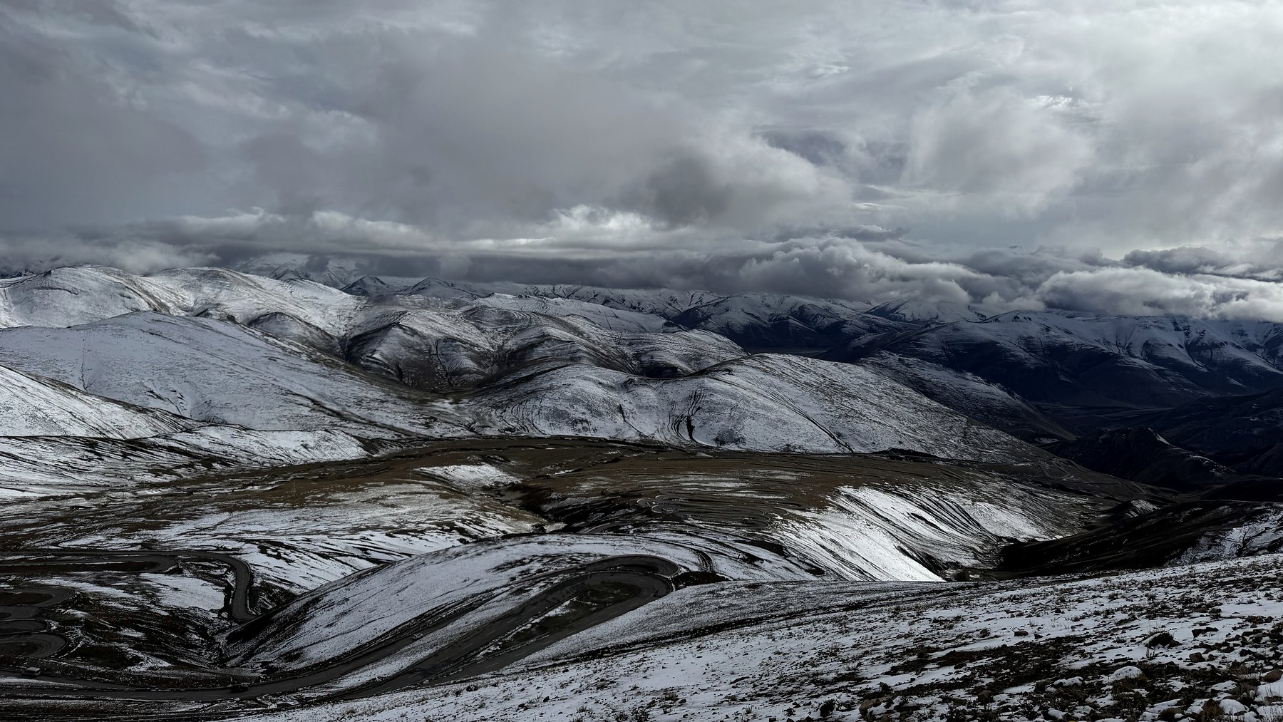 A snow-covered high-altitude road beneath low cloud