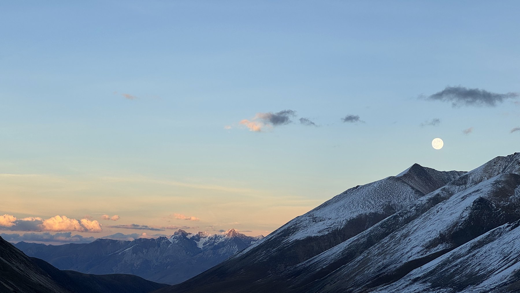 The moon above a snow-covered ridge at dusk